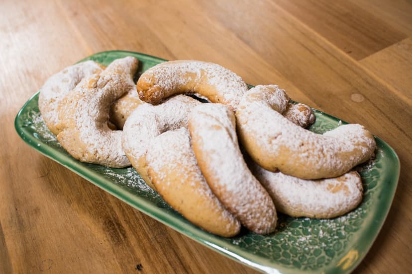 Powdered sugar crescent cookies on a green ceramic platter